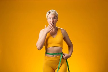 Sarı arka planda kısa saçlı, mezuralı bir kadın. Kilo kaybı ve sağlık konsepti
