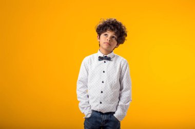 Gülümseyen mutlu çocuk 6-7 yaşlarında. Sarı arka plandaki stüdyoda