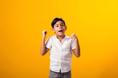 Çocuk portresi sarı arka planda kazanan hareketi gösteriyor. Başarı ve zafer kavramı