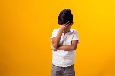 Kafasını sarı arka planda tutan üzgün çocuk portresi. Duygular ve zorbalık kavramı