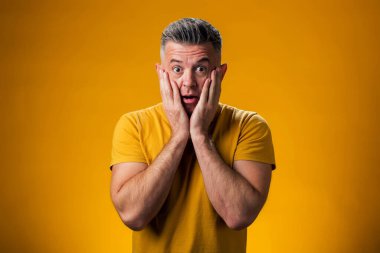 Heyecanlı ya da şaşırmış bir adamın portresi. İki eli de suratında. İnsanlar ve duygu kavramı