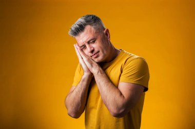 Sarı arka planda uyku jesti gösteren bir adam portresi. Rahatlama kavramı