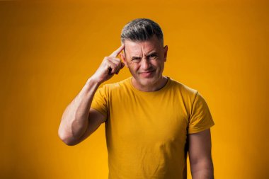 Gülümseyen adamın kafaya parmağıyla dokunuşunun portresi sarı arkaplan üzerinde harika bir fikir hareketi gösteriyor.. 