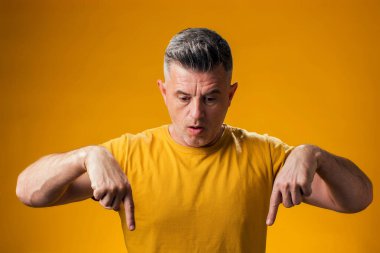 Şaşırmış bir adamın portresi sarı arka planı işaret ediyor. Reklam kavramı