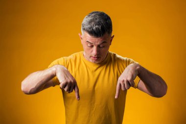 Şaşırmış bir adamın portresi sarı arka planı işaret ediyor. Reklam kavramı