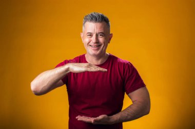 Büyük ve büyük boyut işareti gösteren el hareketleriyle insan portresi, sarı arkaplan üzerinde ölçü sembolü 