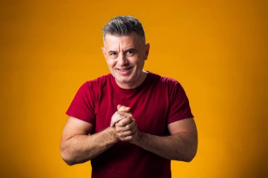 Sarı arka planda ellerini ovuşturan gülümseyen adamın portresi. Başarı ve iyimser konsept