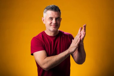 Gülümseyen adamın portresi alkışlıyor ve mutlu ve neşeli bir şekilde alkışlıyor sarı arka planda.