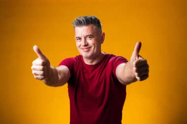 Sarı arka planda baş parmağını gösteren bir adam portresi. İnsanlar ve duygu kavramı