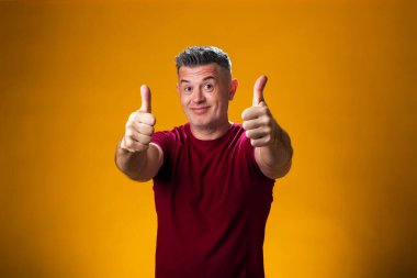 Sarı arka planda baş parmağını gösteren bir adam portresi. İnsanlar ve duygu kavramı