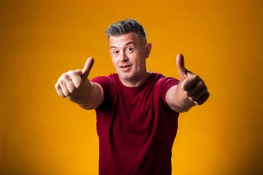 Sarı arka planda baş parmağını gösteren bir adam portresi. İnsanlar ve duygu kavramı