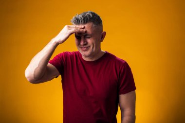 Acı ve migren yüzünden çaresiz ve stresli bir adamın portresi. Ellerini başının üstüne koy. Halk, sağlık ve tıp konsepti