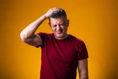 Kafası karışık bir adamın portresi, sarı arka planda sorunlar, hayatla ilgili sorunlar. Negatif insan duyguları konsepti.