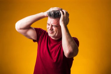 Kafası karışık bir adamın portresi, sarı arka planda sorunlar, hayatla ilgili sorunlar. Negatif insan duyguları konsepti.