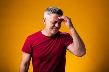 Acı ve migren yüzünden çaresiz ve stresli bir adamın portresi. Ellerini başının üstüne koy. Halk, sağlık ve tıp konsepti