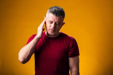 Kulak ağrısından muzdarip bir adamın portresi. El kulakta, sarı arka planda. Halk, sağlık ve tıp konsepti