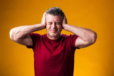 Acı ve migren yüzünden çaresiz ve stresli bir adamın portresi. Ellerini başının üstüne koy. Halk, sağlık ve tıp konsepti