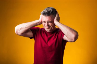 Acı ve migren yüzünden çaresiz ve stresli bir adamın portresi. Ellerini başının üstüne koy. Halk, sağlık ve tıp konsepti