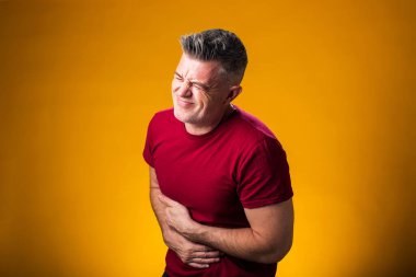 Mide ağrısı çeken bir adamın portresi. Mide ağrısı ve diğer karın hastalıkları. Göbek bölgesindeki ağrı ve yaralanmayı göstermek için adamın eli beline dolanmış. Halk, sağlık ve tıp konsepti