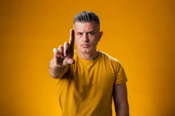 Portrait of serious man pointing with finger up and angry expression, showing no gesture