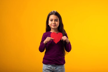 Elinde kağıt kulaklı sarı arka plan tutan çocuk portresi. Aşk, ilgi ve Sevgililer Günü konsepti