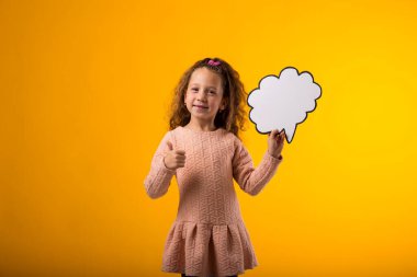 Elinde bulut baloncuğu kartı olan gülümseyen bir kızın portresi ve sarı arka planda baş parmağını kaldırma hareketi. Rüya kavramı