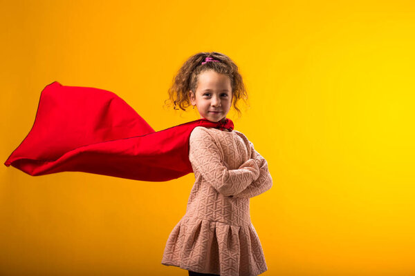 Portait Kid Girl Superhero Red Cloak Yellow Background Concept Victory Stock Image