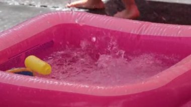 Şişme yüzme havuzu ve yazın çocukların oynaması için soğuk su spreyi.