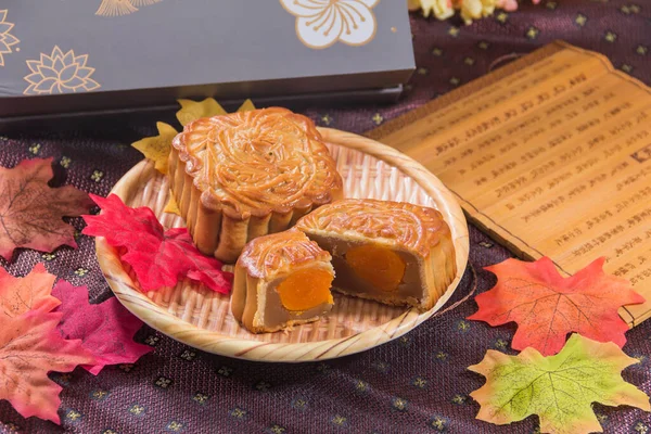 Moon cake and autumn leaves on wooden plate, Chinese mid autumn festival food
