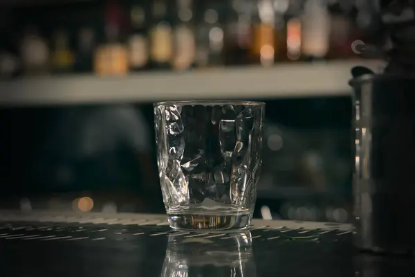 Glass of whiskey and ice on bar counter in pub or restaurant.