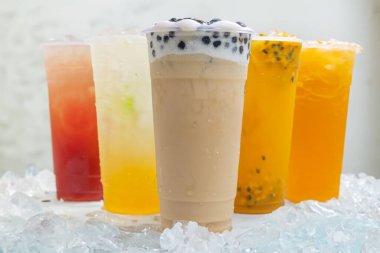 Tayvan Boba sütlü çayı ve Passion meyveli içecekler beyaz arka planda buzlu plastik bardakta.