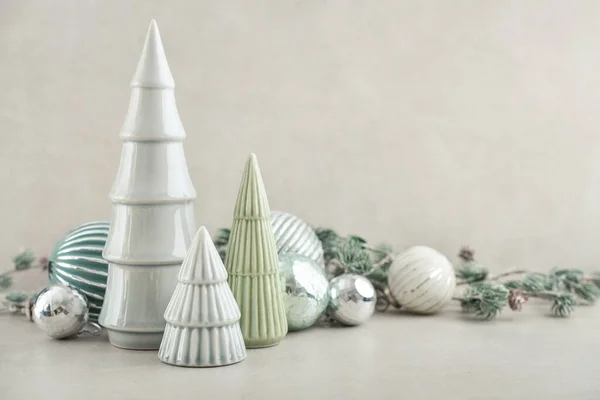 Dekorative Keramiktannenbäume Mit Weihnachtskugeln Und Tannenzweigen Auf Hellem Hintergrund — Stockfoto