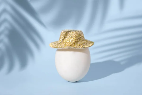 Одно Белое Куриное Яйцо Маленькой Летней Соломенной Шляпе Голубом Фоне — стоковое фото