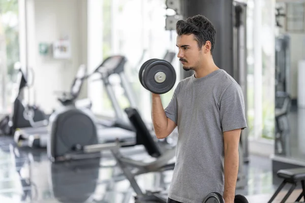 A man in contemplation, preparing to lift weights. This image captures the moment of mental preparation in sports and fitness.Mental preparation for physical activity concept