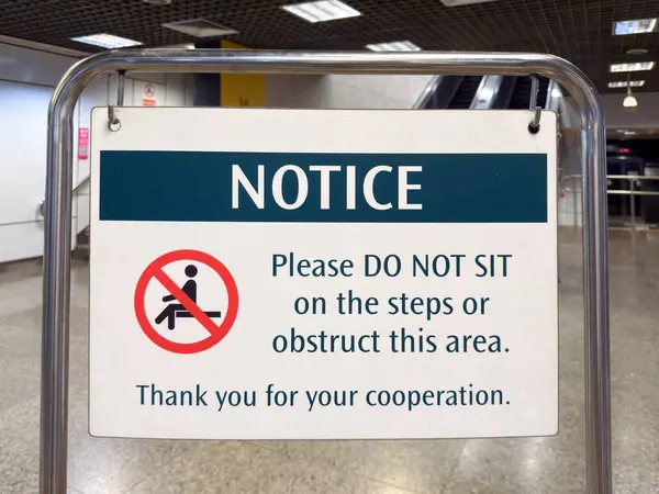Singapur, Singapur - 1 Mayıs 2025: Basamaklarda oturmaya ya da bölgeyi kapatmaya karşı bir uyarı. Oturulmayan bir sembol ve işbirliği talebi içeriyor..