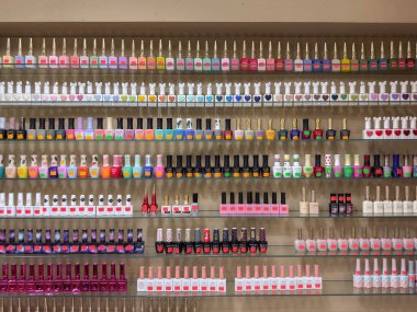 Penang, Malezya - 24 Nisan 2025: çeşitli renklerde tırnak cilası şişeleri düzenli olarak raflarda düzenlenir, müşteriler için canlı gölgeler ve stiller sergilenir.