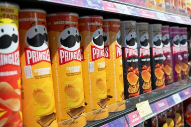  Çedar peyniri, acı ve baharatlı gibi seçenekler sunan bir süpermarket rafında çeşitli aromalı Pringles konserveleri düzenli olarak düzenlenir..