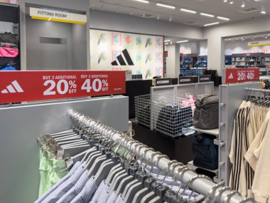 Penang, Malezya - 22 Nisan 2025 mağaza vitrinlerinde% 20 indirim ve% 40 indirim için tabelaları olan elbise ve aksesuarlar sergileniyor. Uyum odası arka planda görünür.