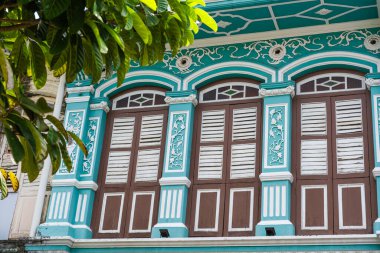 Penang, Malezya 23 Temmuz 2025 Vibrant turkuaz koloni binası. Karmaşık kepenkler ve bereketli yeşilliklerle çevrili klasik tasarım elementleri..