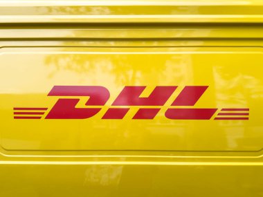 Penang, Malezya - 25 Haziran 2025: Parlak sarı bir teslimat aracı DHL logosunu kırmızı ile gösteriyor, açıkça görülüyor, şirketlerin marka kimliğini vurguluyor..