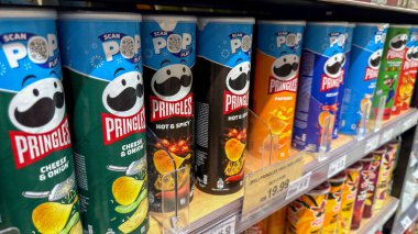Penang, Malezya - 7 Temmuz 2025: Peynir ve soğan, sıcak ve baharatlı ve kırmızı biber gibi tatlarda Pringles atıştırmalıkları dolu raflar