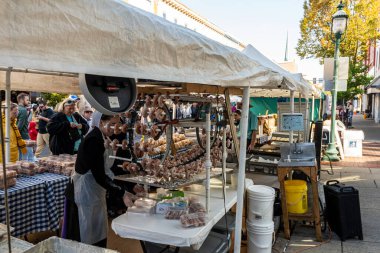 Chambersburg Pennsylvania ABD 10-15-2022 Amish kız güneşli sonbahar gününde bisiklet tekerleklerini kullanarak açık hava festivalinde donut yapıyor.