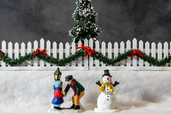 横クリスマスシーンとともに父と娘の人形雪のランプポストと雪だるまの横に — ストック写真