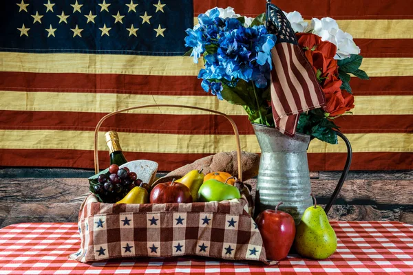picnic basket on checkered table cloth bouquet of flowers and American flag background