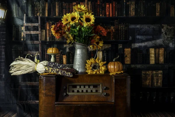 vintage radio decorated for autumn with pumpkins sunflowers and corn with old library background