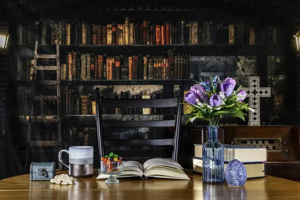 アンティークラジオと木の十字の背景を持つ古い図書館のテーブルに春の花とゼリー豆 ストック写真