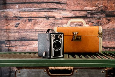 Antika kutu kamerası ve eski bavul ahşap arka planlı yeşil kepenk üzerinde