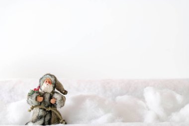 Santa Claus in grey fur wading through deep snow to deliver Christmas presents with white background and room for copy clipart