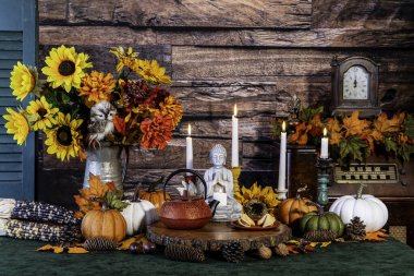 maximalist autumn tea party with buddha fortune cookies pumpkins sunflowers and burning candles with rustic wood background