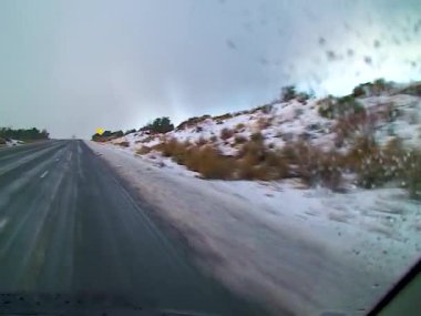 A car drives slowly at night on a slippery snowy road in the USA